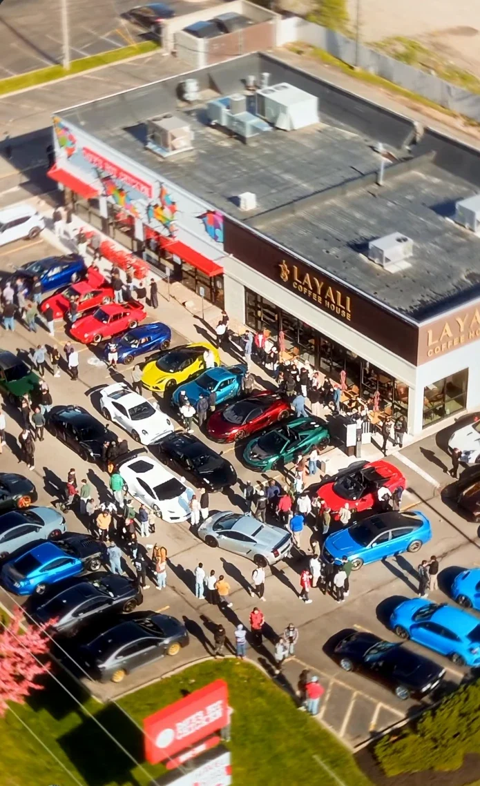 Aerial view of a packed local car meet with exotics and client builds lined up